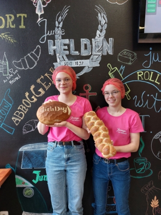 Zwei Mädchen mit Haarnetzen halten Brote in der Hand