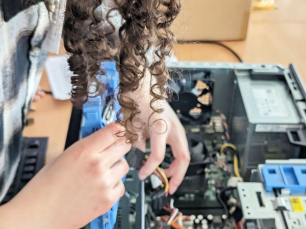 Mädchen tauscht Stecker in Computergehäuse