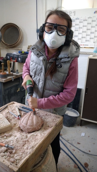 Mädchen mit Schutzmaske bei Steinmetzarbeiten