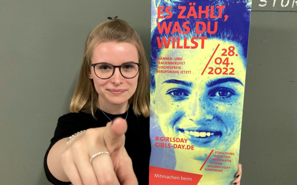 Junge Frau mit Plakat zeigt in die Kamera