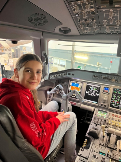 Mädchen sitzt am Steuer im Cockpit eines Flugzeugs.