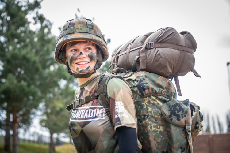 Person in Bundeswehrausrüstung und Tarnfarbe im Gesicht