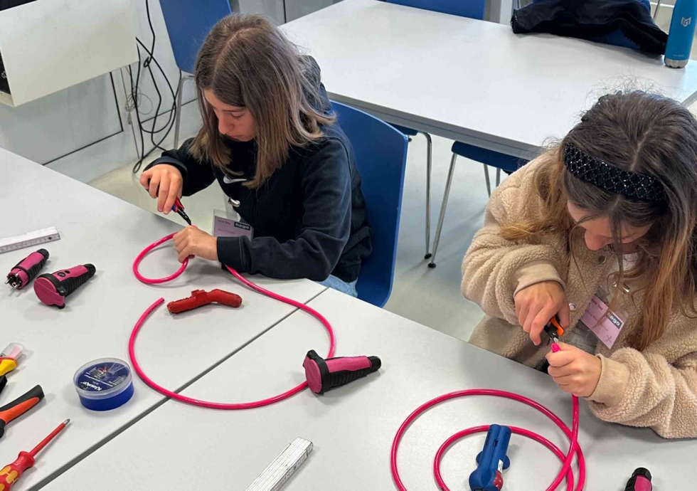 Girls'Day-Teilnehmerinnen arbeiten am Tisch mit Kabeln