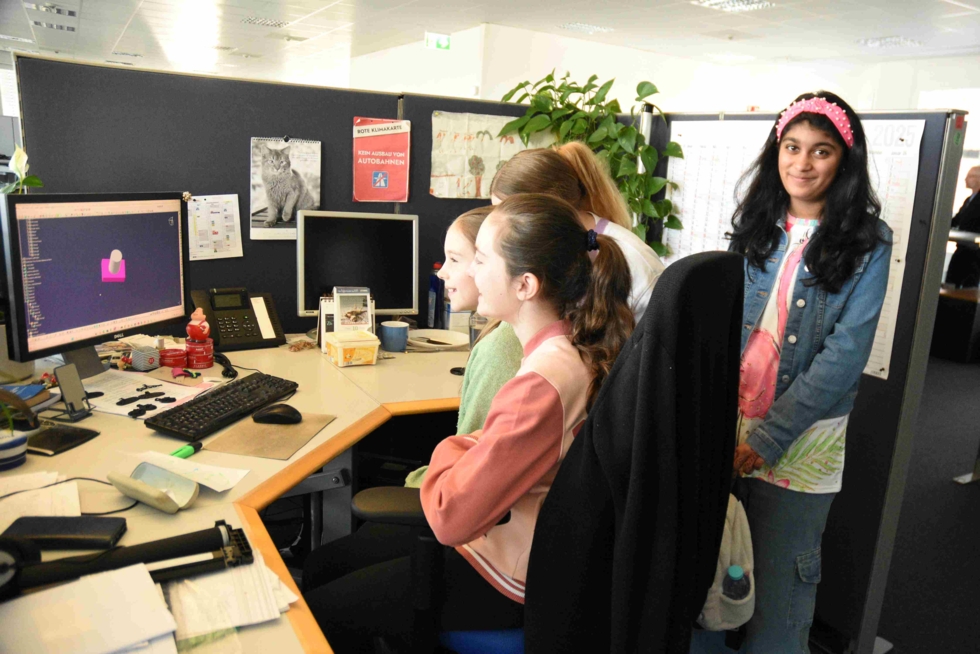 Vier Girls' Day-Teilnehmerinnen schauen auf einen Computerbildschirm in einem Büro