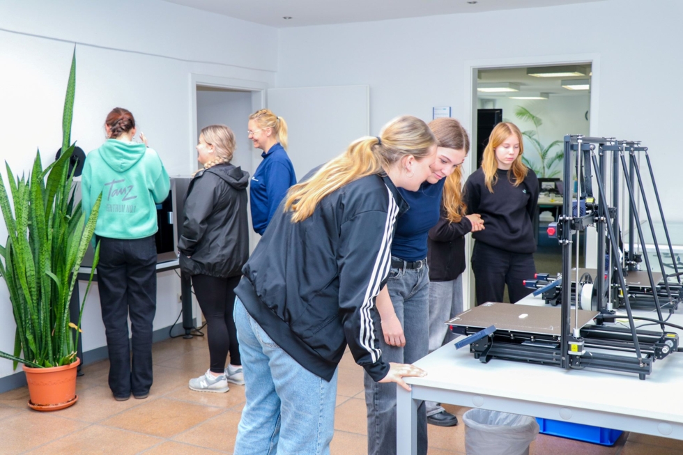 Girls' Day-Teilnehmerinnen betrachten einen 3D-Drucker in einem hellen Raum