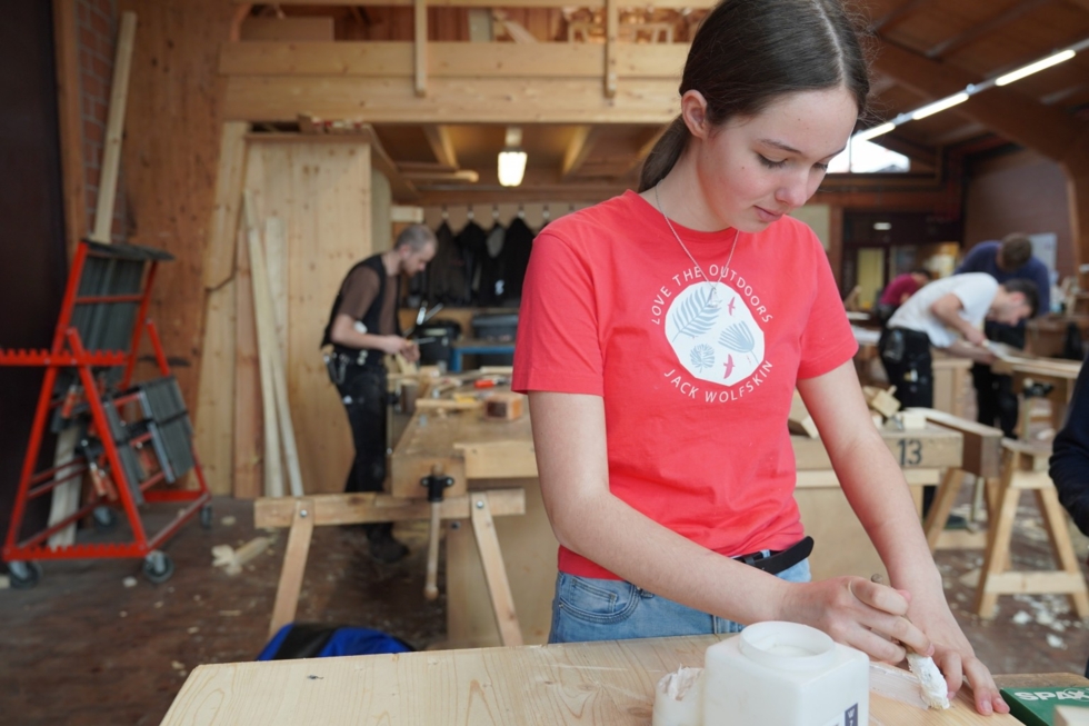 Girls'Day-Teilnehmerin leimt ein Stück Holz