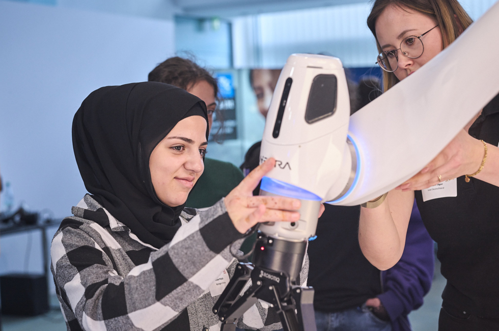 Mädchen berührt den Roboterarm mit der Hand