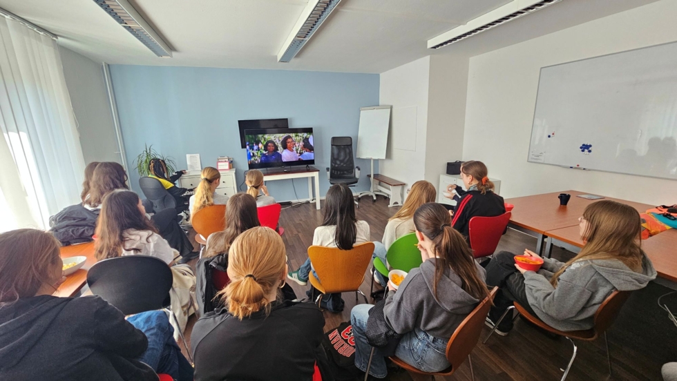 Girls' Day-Teilnehmerinnen sitzen in einem Klassenraum und schauen einen Film auf einem Fernseher an
