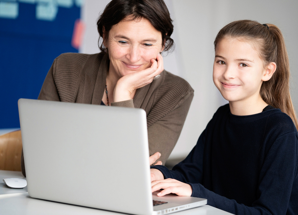 Eine Frau und ein Mädchen sitzen vor einem Laptop