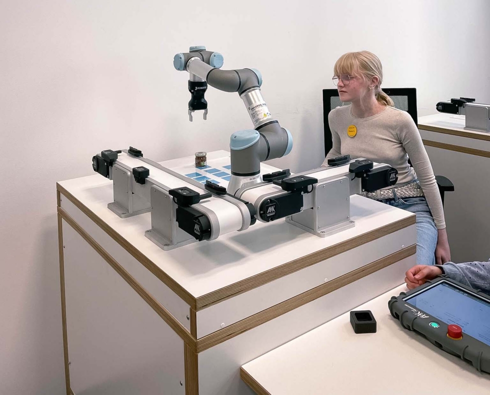 Girls'Day-Teilnehmerin am Tisch mit Roboterarm