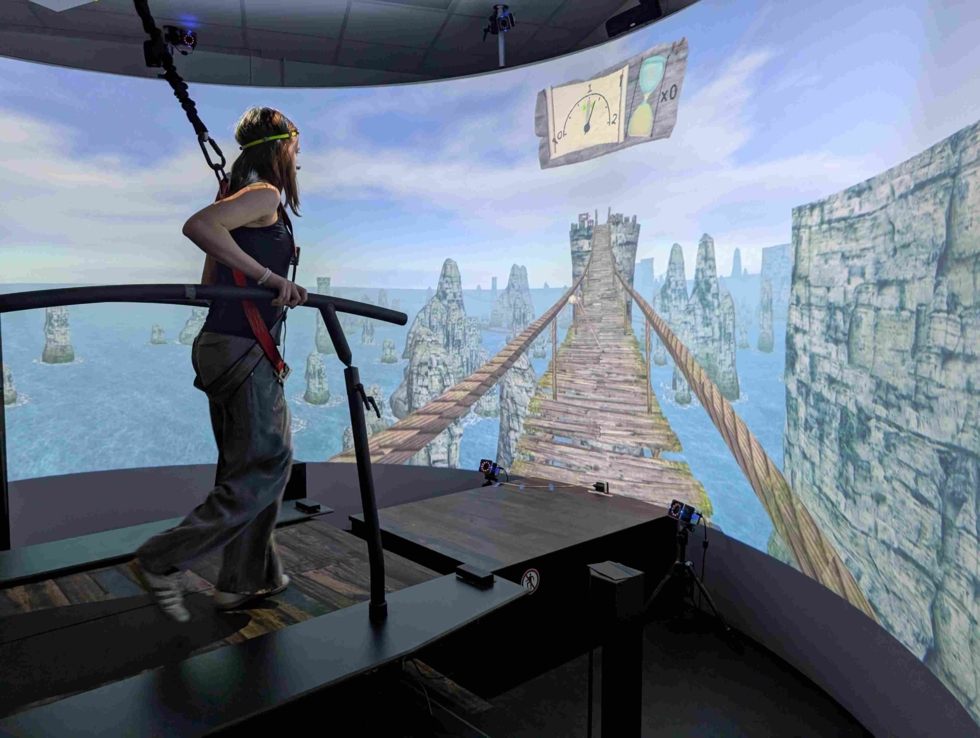 Person auf Laufband mit VR-Brille, die eine virtuelle Hängebrücke über Wasser erkundet