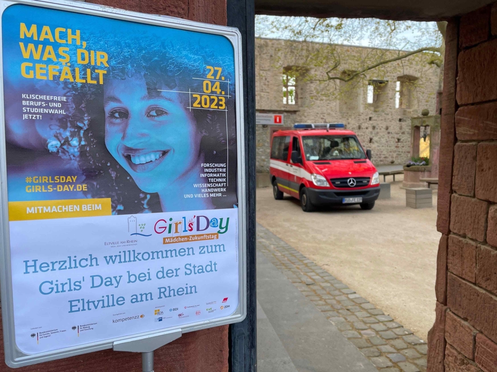 Girls'Day-Plakat mit Schriftzug der Stadt Eltville und einem Feuerwehrauto im Hintergrund