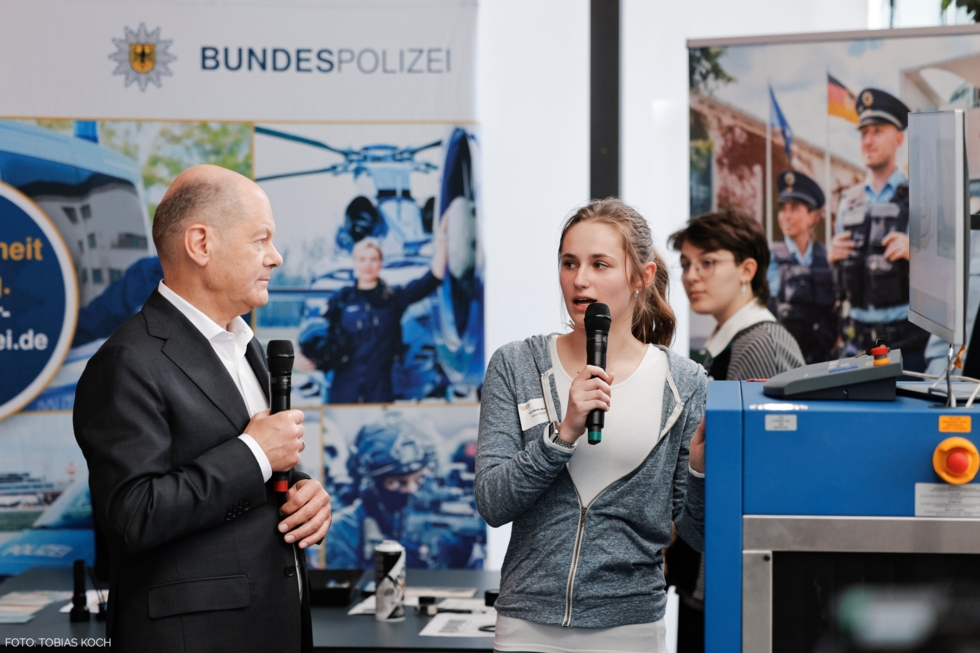 Eine Girls'Day-Teilnehmerin spricht am Stand der Bundespolizei mit Bundeskanzler Olaf Scholz.
