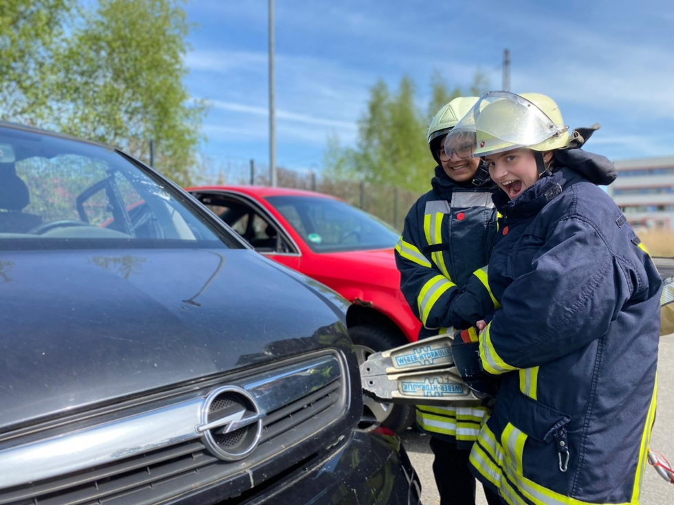 Mädchen in Feuerwehrausrüstung mit einer hydraulischen Zange