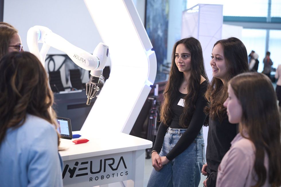 Schülerinnen stehen neben einem Roboter